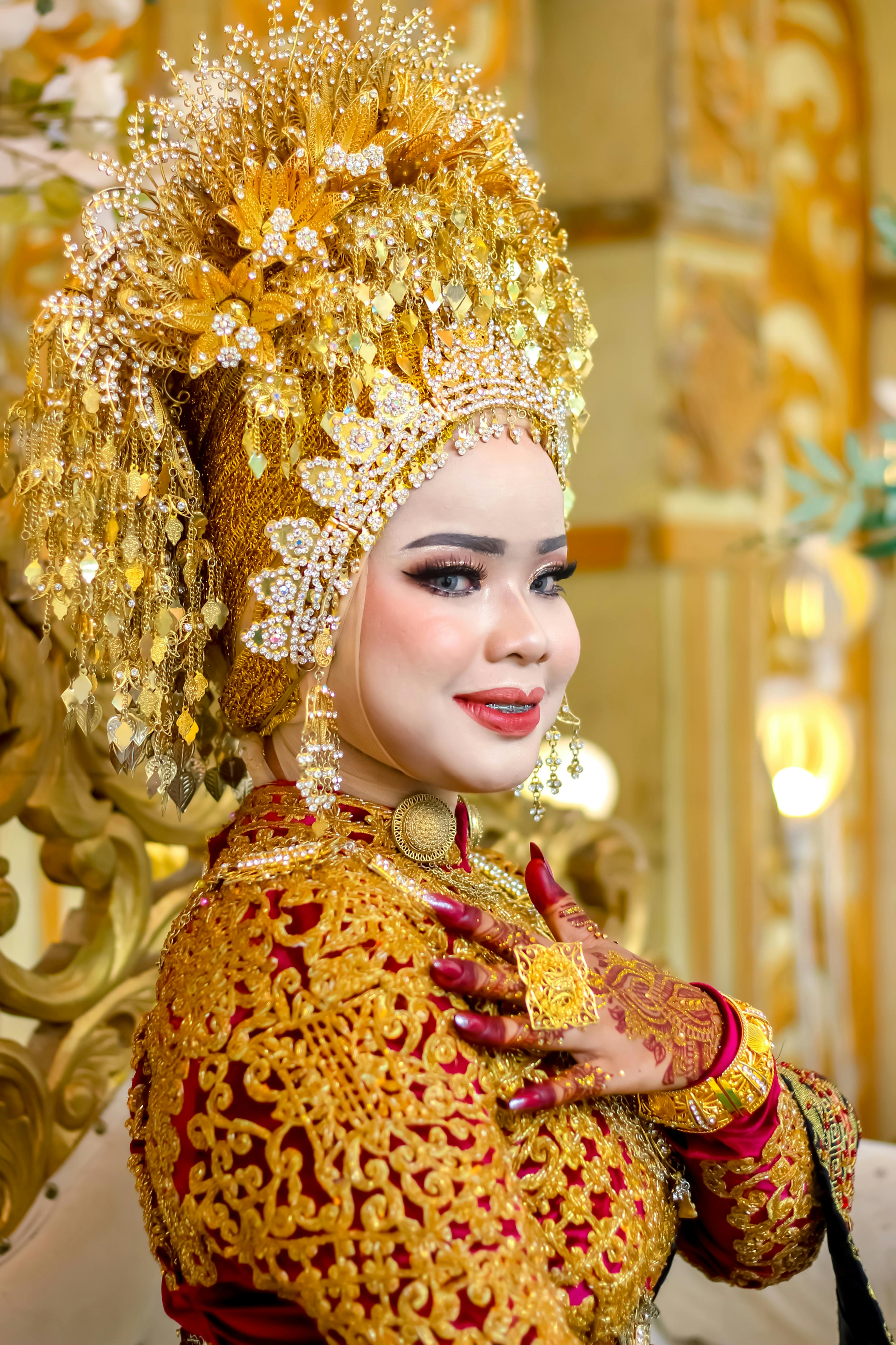 Portrait of an Acehnese bride in intricate traditional gold attire and elaborate headpiece.