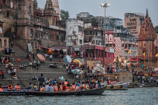 Lively scene of boats and people along the Ganges riverfront in Varanasi, India.