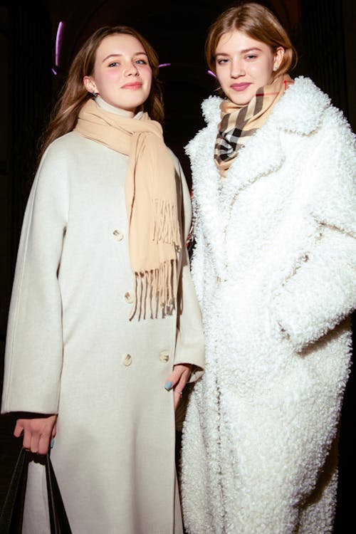 Two Young Women in Coats Standing in the Dark