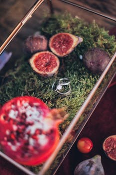 这款以无花果和石榴片为特色的复杂设置，将优雅的戒指置于天然苔藓床上