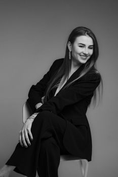 Elegant black and white portrait of a woman in a stylish black blazer posing in a studio setting.