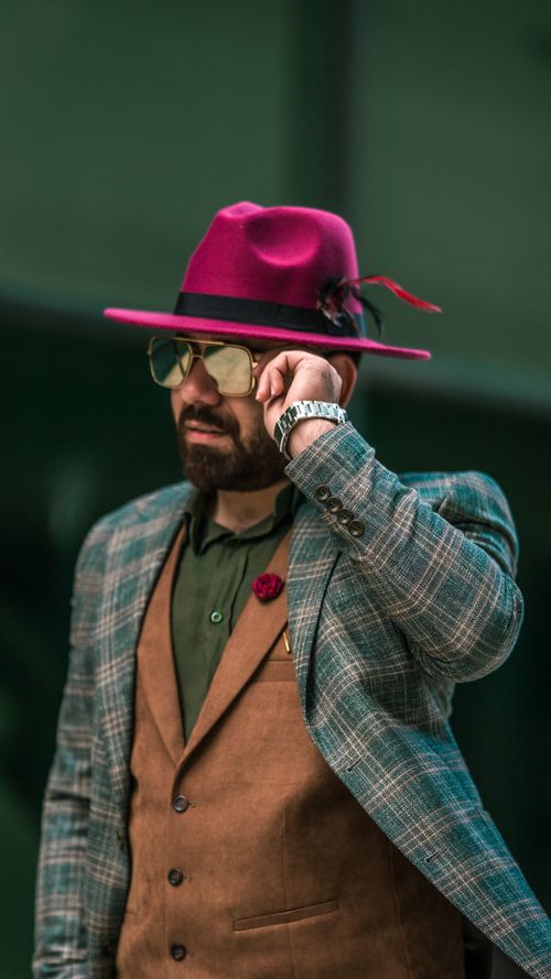 Free Fashionable man in a vibrant pink hat poses confidently in an urban setting, showcasing his style. Stock Photo