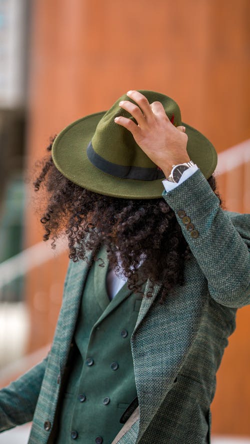 Model Holding Onto a Green Fedora Wearing a Tweed Blazer over a Green Double-Breasted Waistcoat