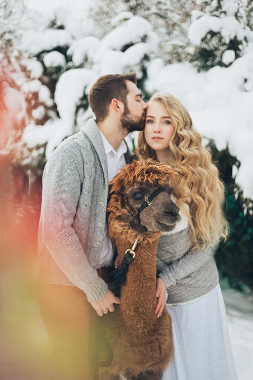 L'uomo E La Donna In Piedi Accanto All'animale Marrone