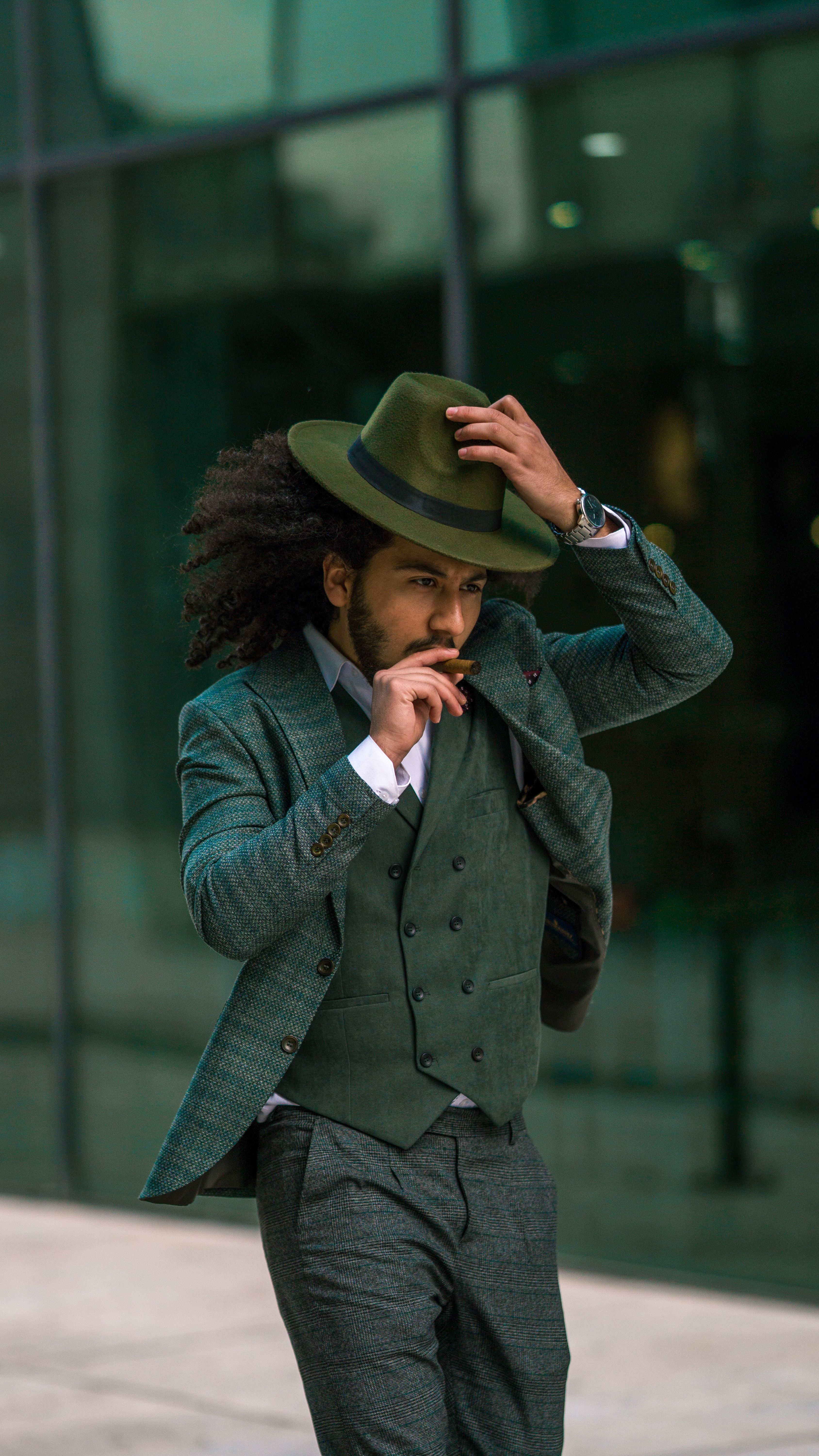 Fashionable man in green suit and hat posing in urban setting. Perfect for modern fashion concepts.