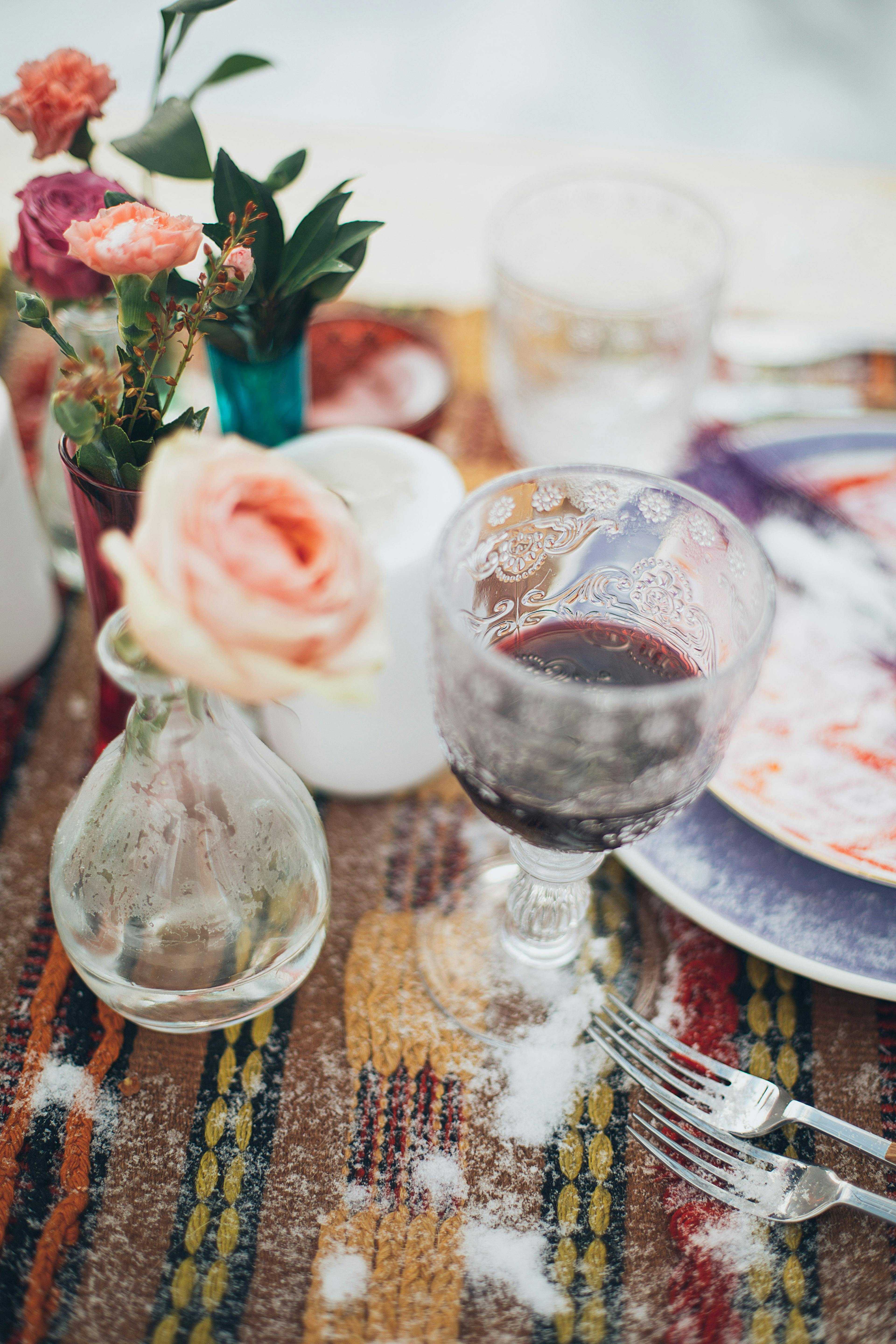 一张摆满鲜花和餐具的五彩桌子上，酒杯的特写营造出优雅的用餐氛围