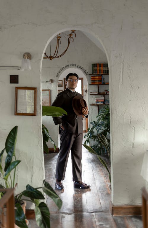 Elegant Man in a Suit and Holding a Hat Standing in a Room 