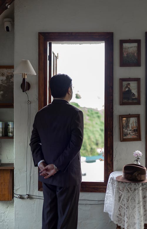 Back View of a Man in a Suit Standing by the Window in a Vintage Room 