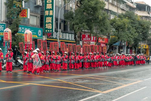 Free Vibrant parade participants in red traditional attire on a rainy urban street. Stock Photo