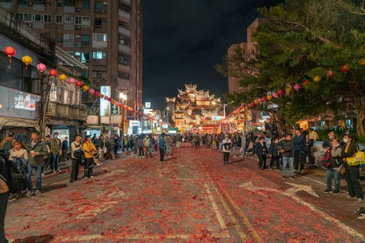 A lively street scene in Taipei with people celebrating at night near a temple.
