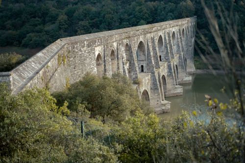 Free Historic Maglova Aqueduct framed by verdant forest, showcasing Ottoman architecture. Stock Photo