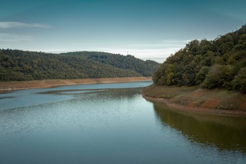 Free Serene river scene with lush hills and calm water, perfect for nature lovers. Stock Photo