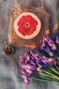 在质朴的织物上，切开的葡萄柚顶视图周围环绕着紫色的鸢尾花