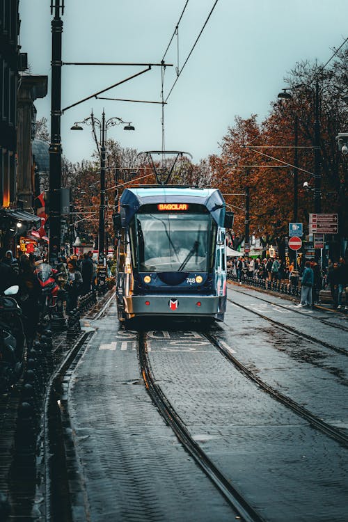A tram is traveling down a street in the rain