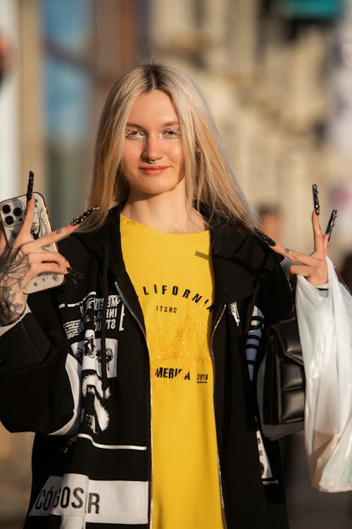 Young Woman in an Oversized T-shirt and Jacket Standing on a Sidewalk 