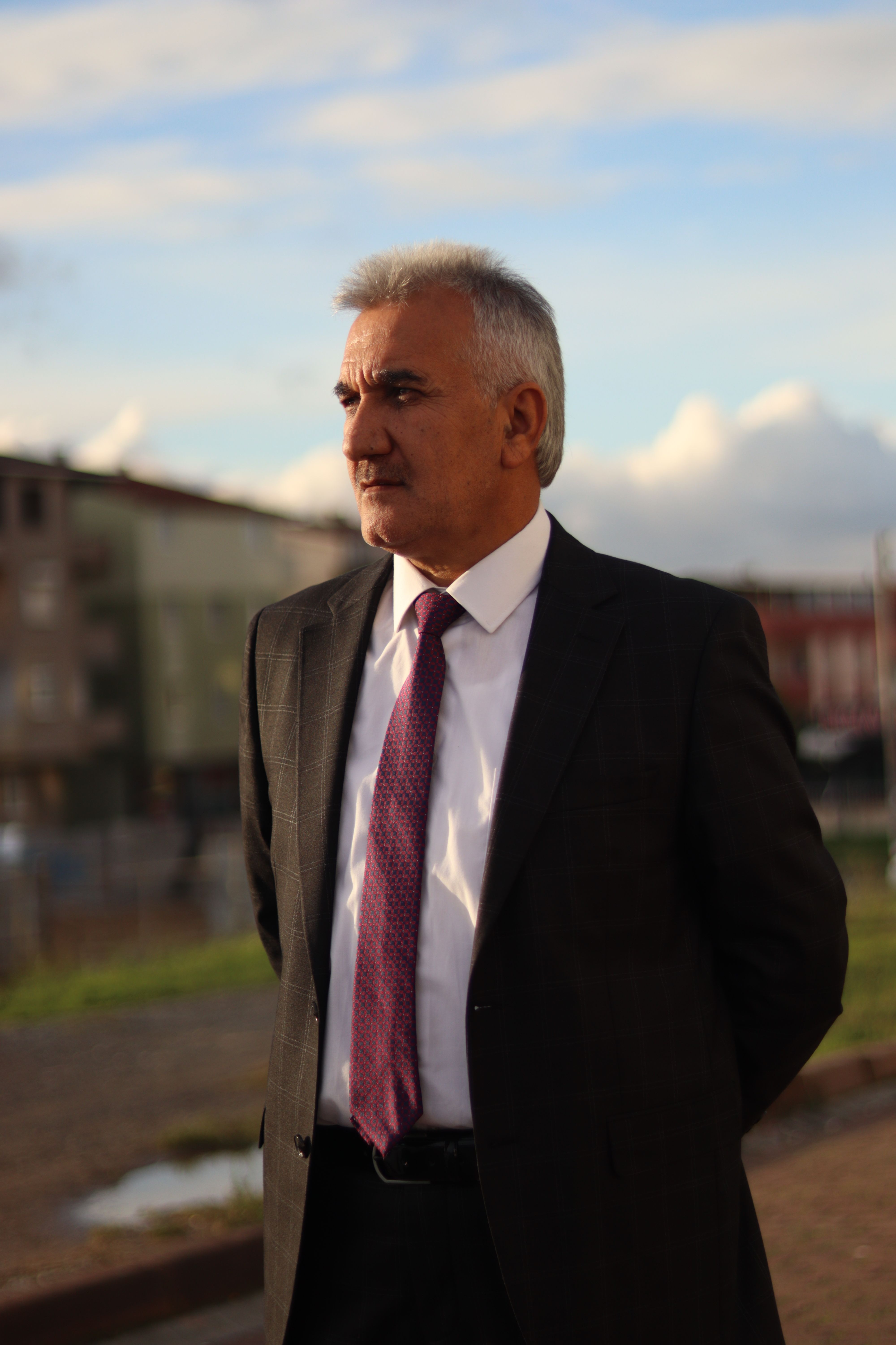 Mature businessman in suit standing outdoors, exuding confidence with urban backdrop.
