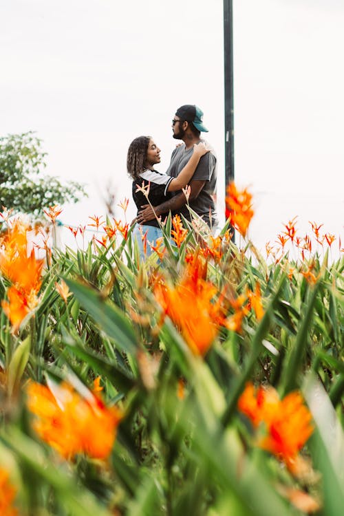 Couple Embracing in a Garden with Orange Flowers