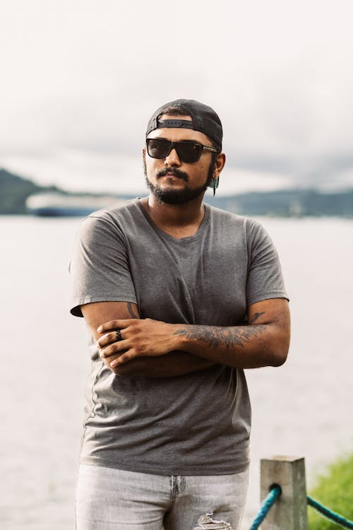 Bearded Man in Sunglasses Standing near a Body of Water 