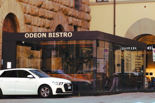 White Audi A1 parked beside Odeon Bistro in urban Florence, showcasing Italian street ambiance.
