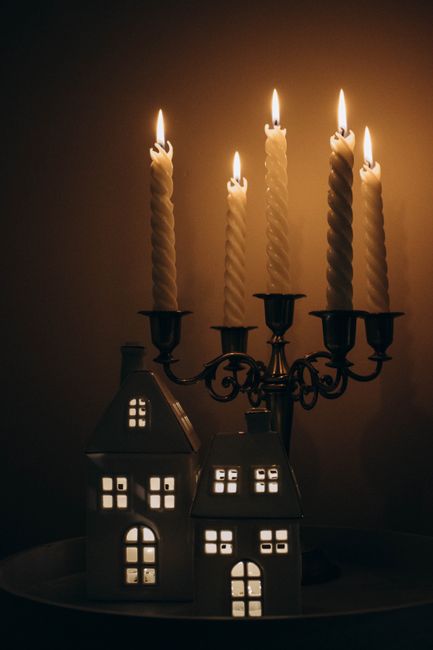 Warm candlelit ambiance with ceramic houses and a vintage candelabrum creates a cozy winter scene.