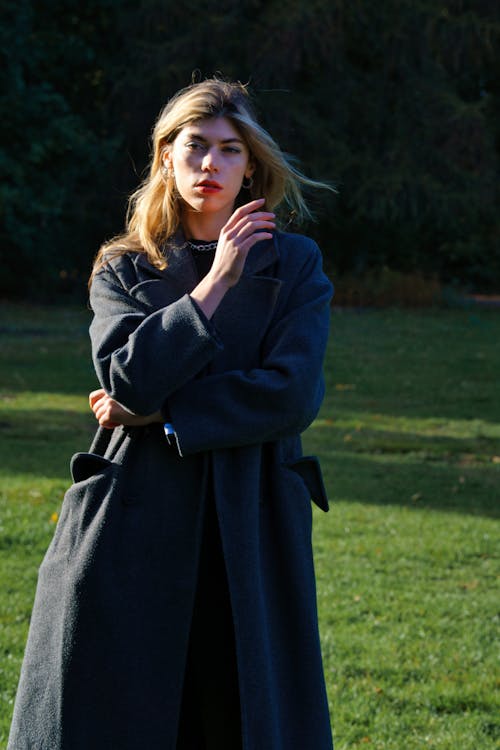 Young Woman in a Coat Standing in a Park 