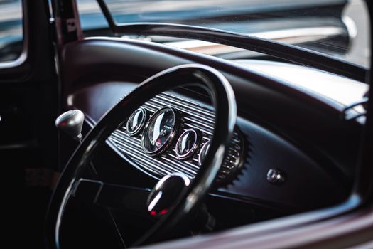 Elegant black and chrome interior of a vintage car showcasing the dashboard and steering wheel.