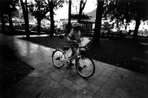 Free A person rides a bicycle through an urban park in monochrome. Stock Photo