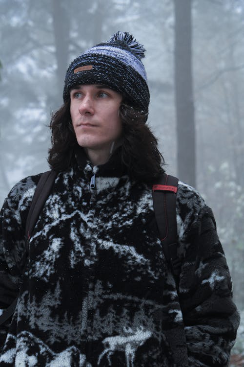 Man with Long Hair and in Hat in Forest in Winter