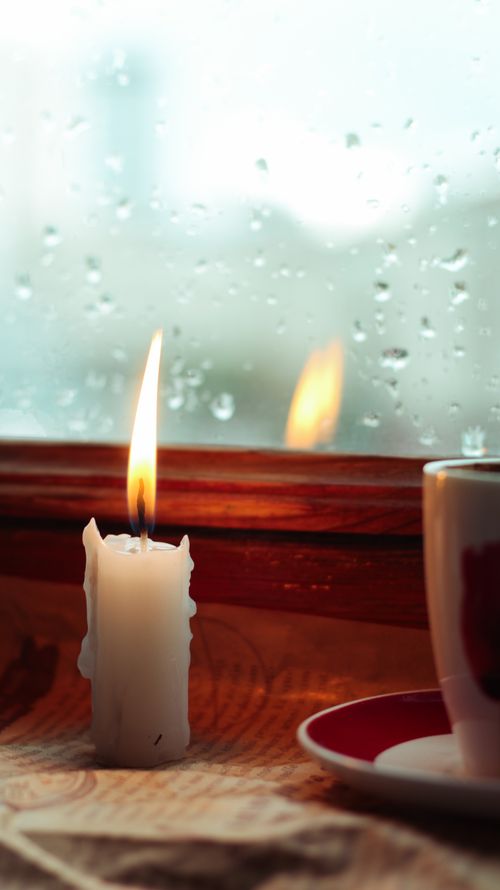 Free Candle burning bright by a rainy window, creating a cozy atmosphere indoors. Stock Photo