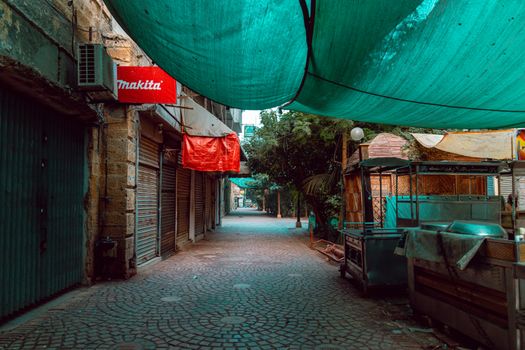 Deserted alleyway in a market with closed stalls and shaded covers.