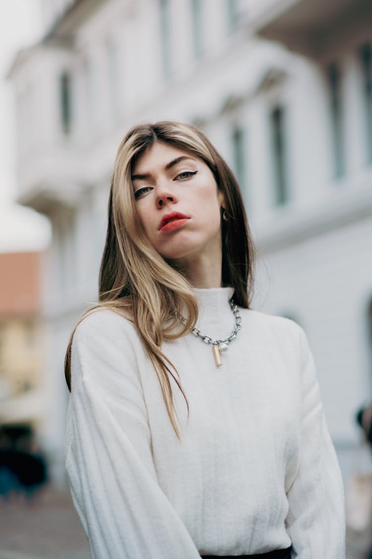 Young Woman In A White Sweater Posing Outside In City 