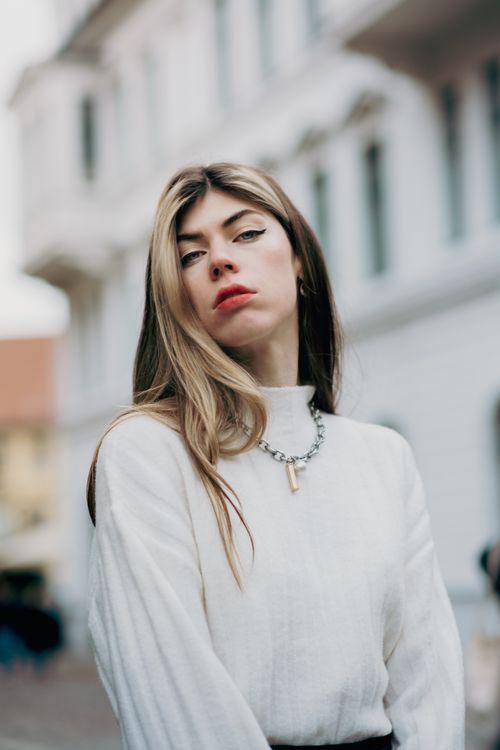 Free Stylish woman in a white sweater posing confidently in an urban outdoor setting. Stock Photo