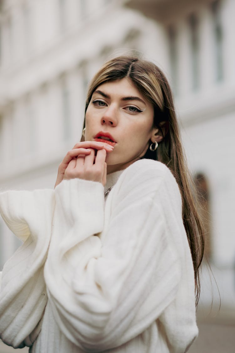 Young Woman In A White Sweater Posing Outside In City 