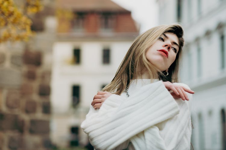 Young Woman In A White Sweater Posing Outside In City 