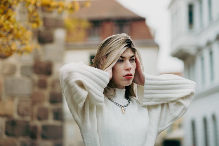 Young Woman In A White Sweater Posing Outside In City 