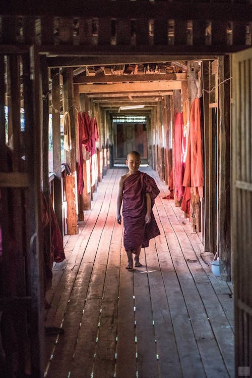 Young Monk Walking in a Wooden Corridor