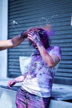 A young person enjoys a vibrant Holi festival with colorful powders outdoors.