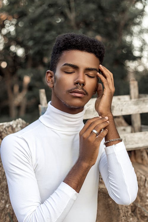 Young Man in a White Turtleneck Standing Outside with Eyes Closed