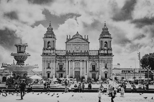 Free Dramatic black and white photo of Guatemala City's historic cathedral with urban activity. Stock Photo
