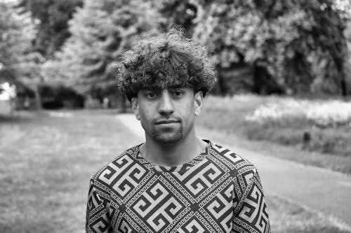 Black and White Portrait of a Young Man with Curly Hair Standing Outside 