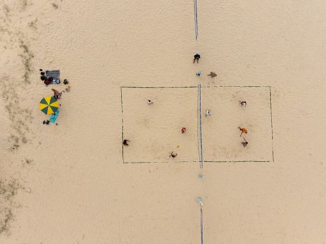 High-angle photo of people playing volleyball on a sandy beach in Australia.