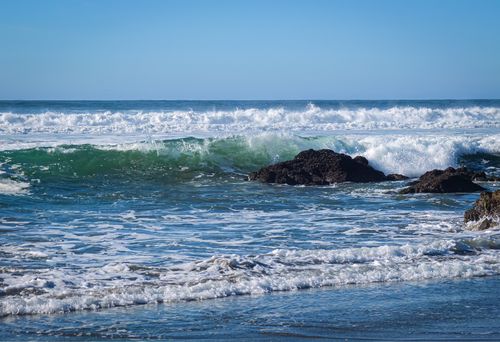 Free Experience the beauty of ocean waves crashing against the rocky shoreline under a clear blue sky. Stock Photo