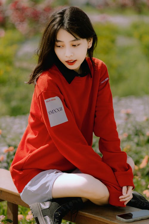 Young Woman in a Red Sweater Sitting Outside 