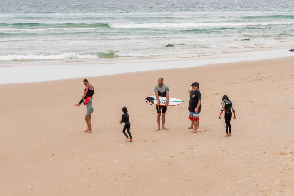 Group enjoying a day at Gold Coast beach with surfboards and wetsuits.