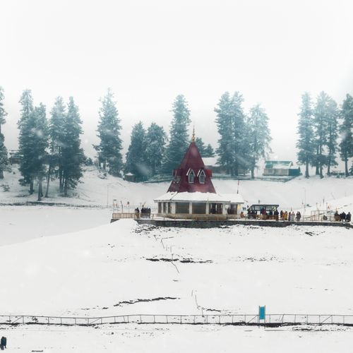 Free A picturesque winter scene of a ski resort with a unique building amidst snow and tall trees. Stock Photo