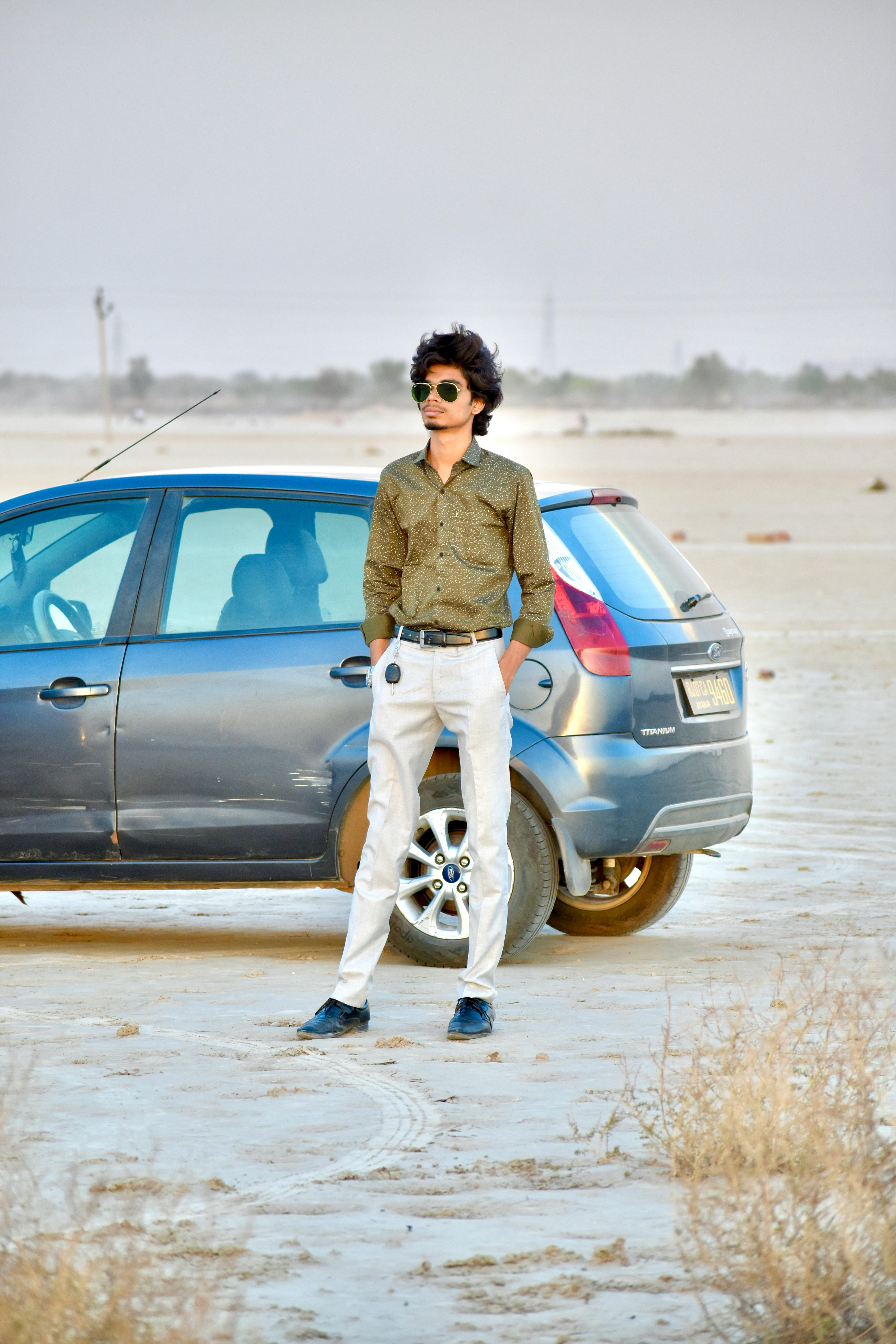 a man standing in the desert next to a car