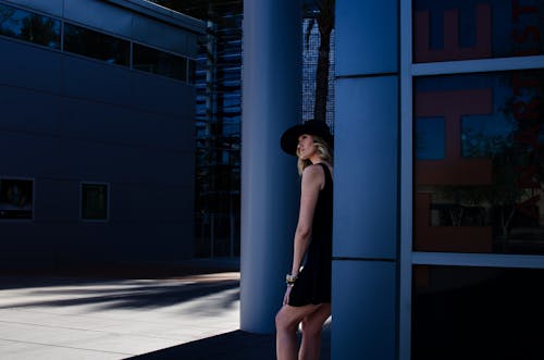 Blonde Model with Hat in Dress Standing by Wall