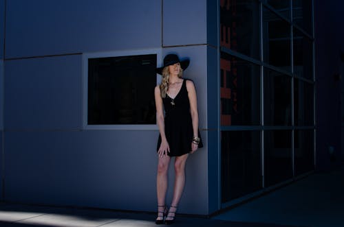 Beautiful Blonde Woman in Black Dress Posing by Wall