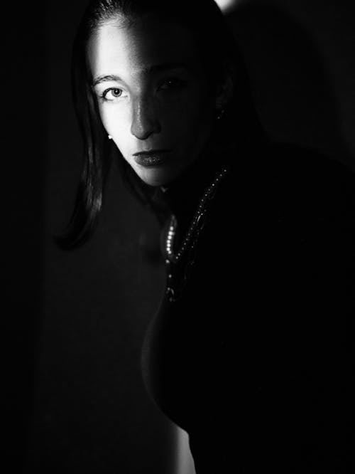 A woman in black and white is looking into the light