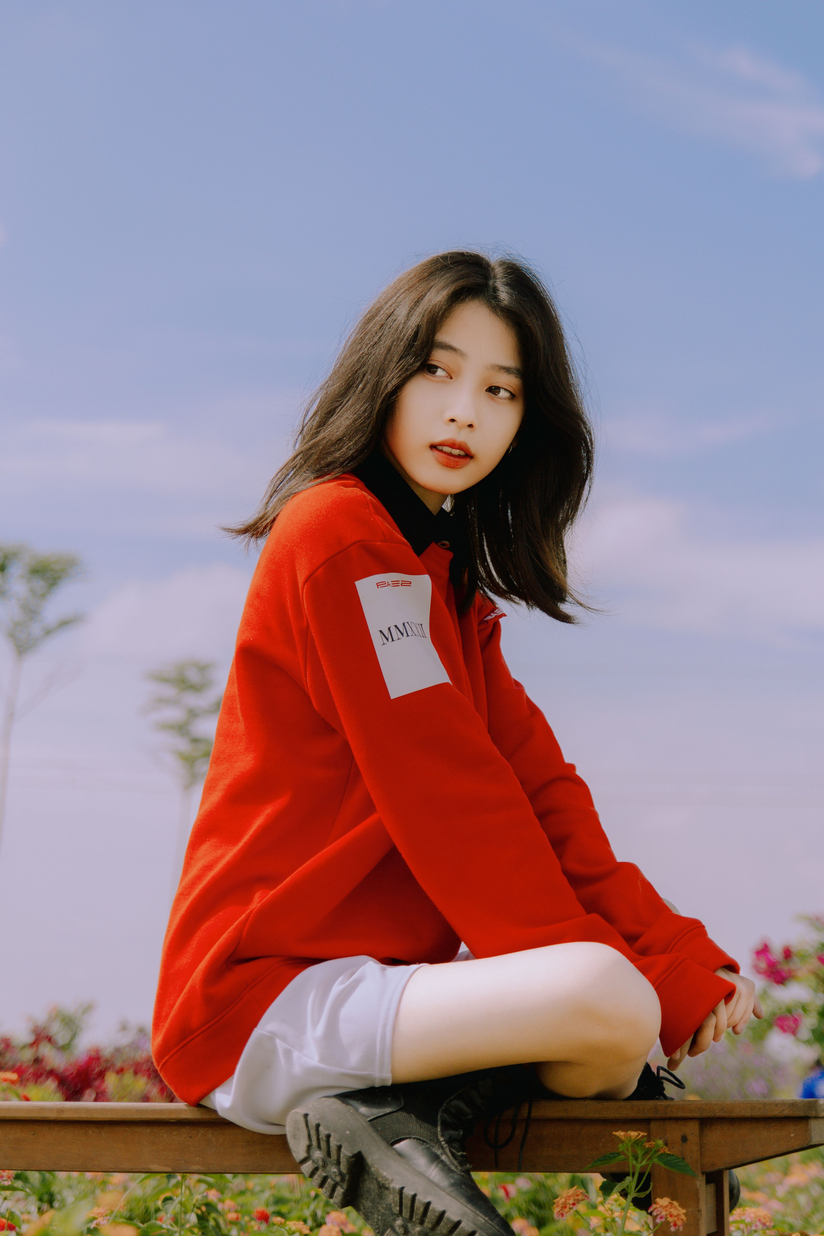 Stylish young woman in a red sweater sitting outdoors, capturing a serene autumn vibe.